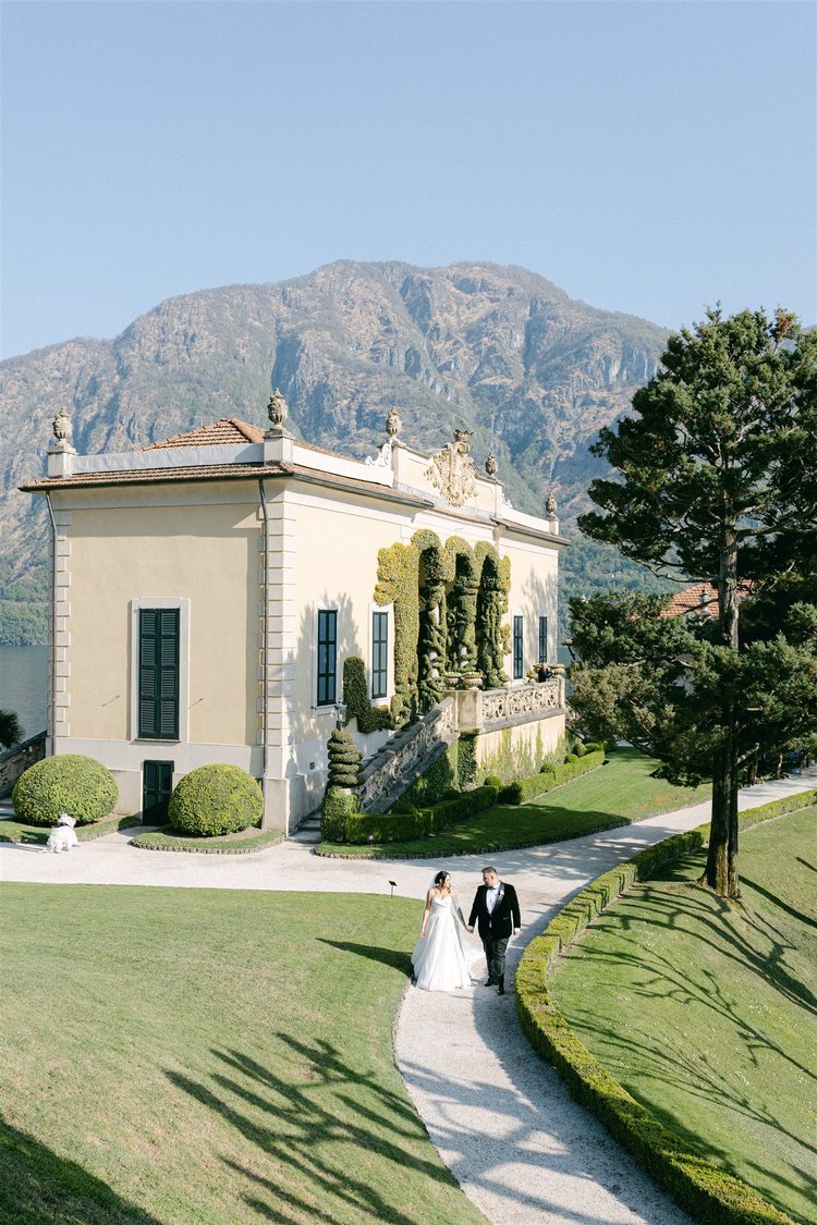 A couple walking through the gardens towards the villa