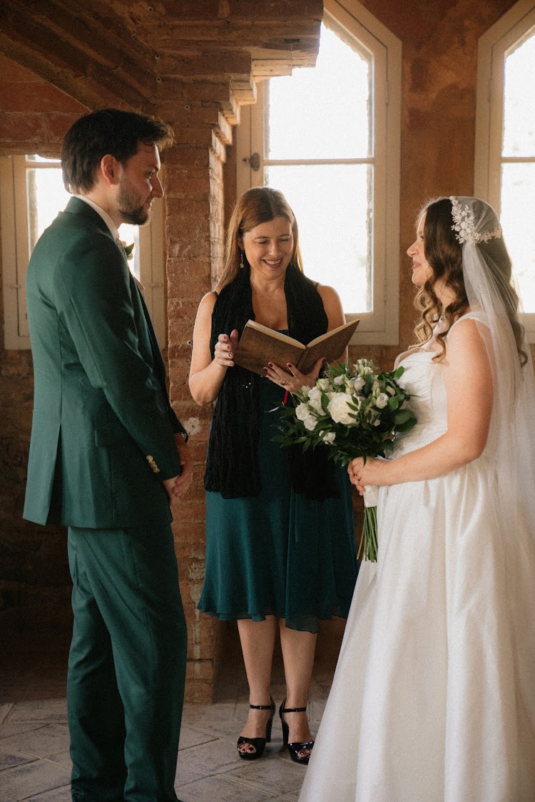 A wedding ceremony inside Bellesguard Tower in Barcelona, with the officiant reading to the couple by the arched windows