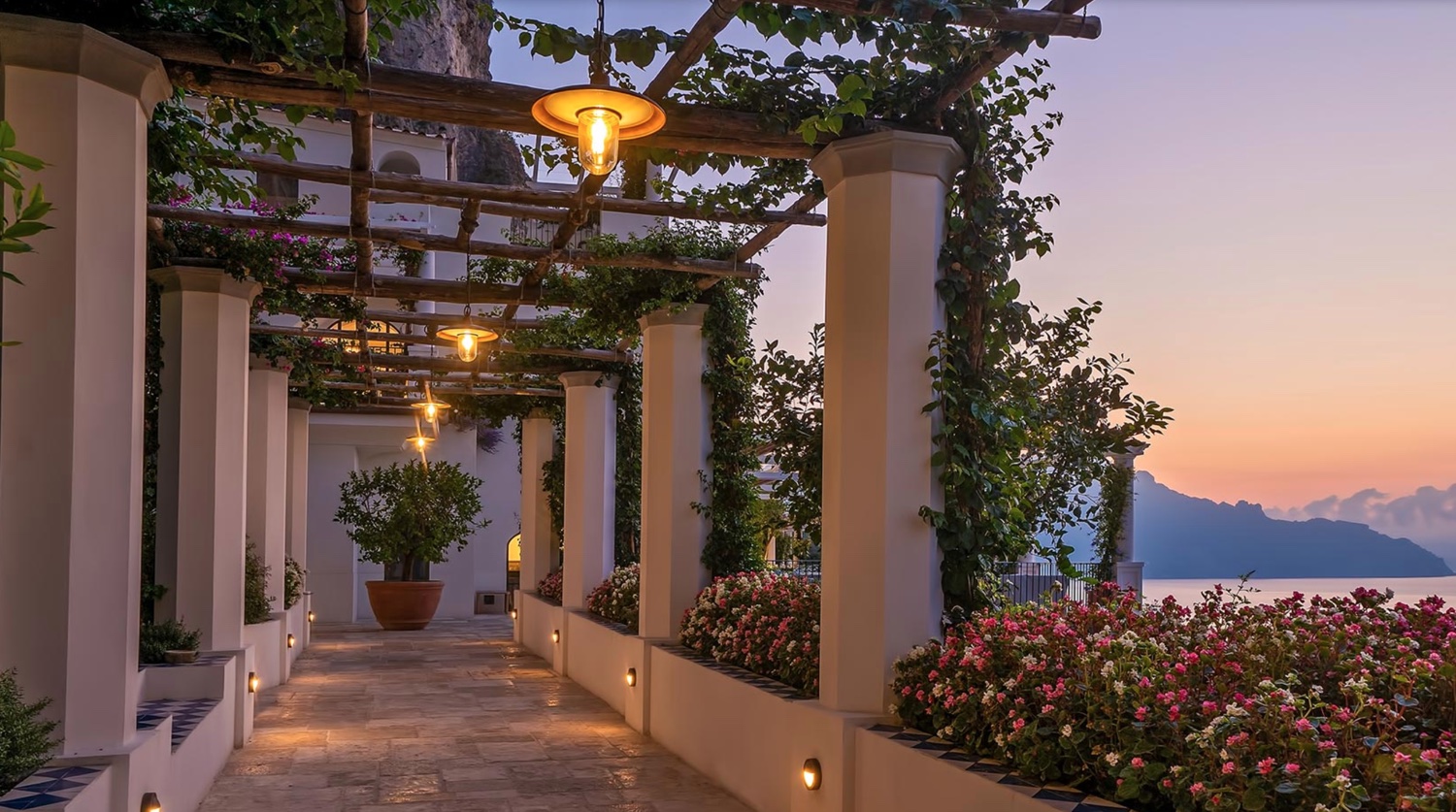 The pergola terrace of Borgo Santandrea at sunset, with bougainvillea and the sea