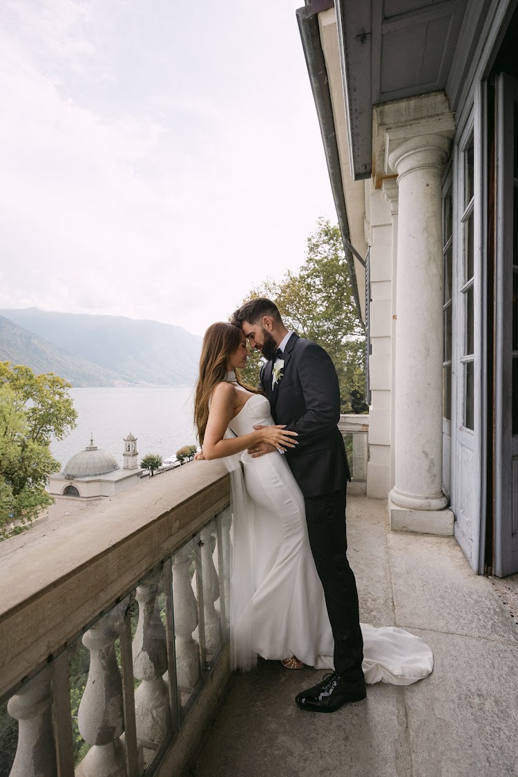 A couple on a balcony of the villa, above the lake