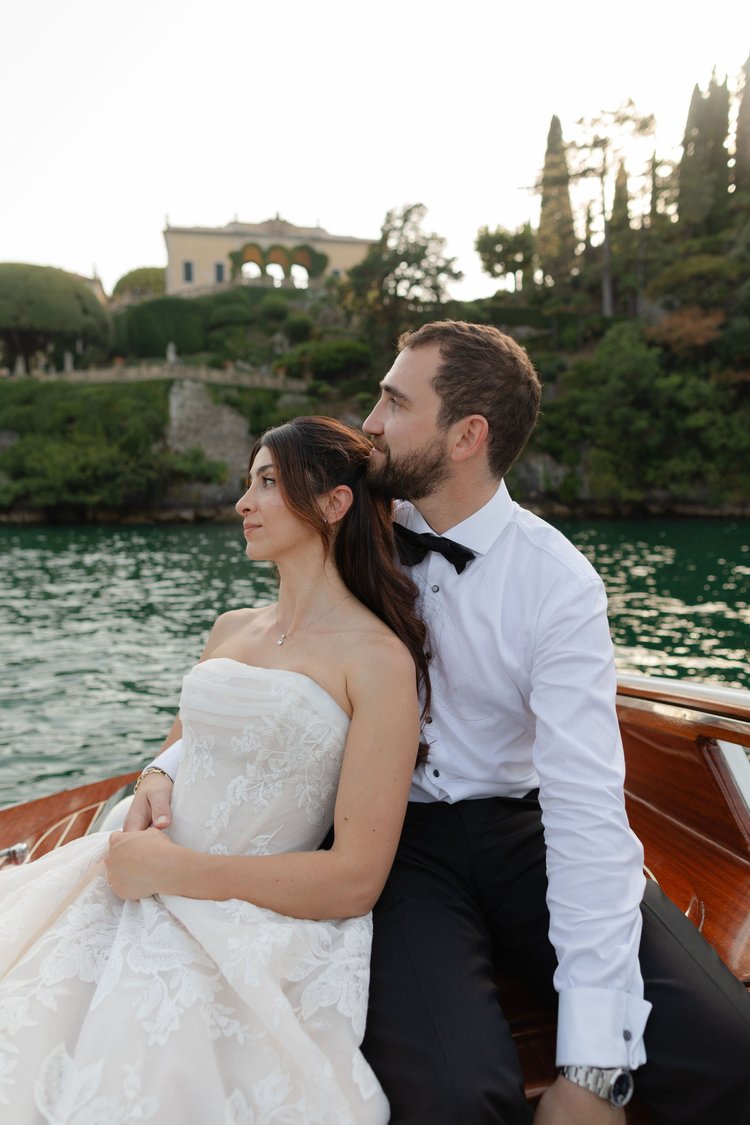 A couple on the boat, with a lakeside villa behind
