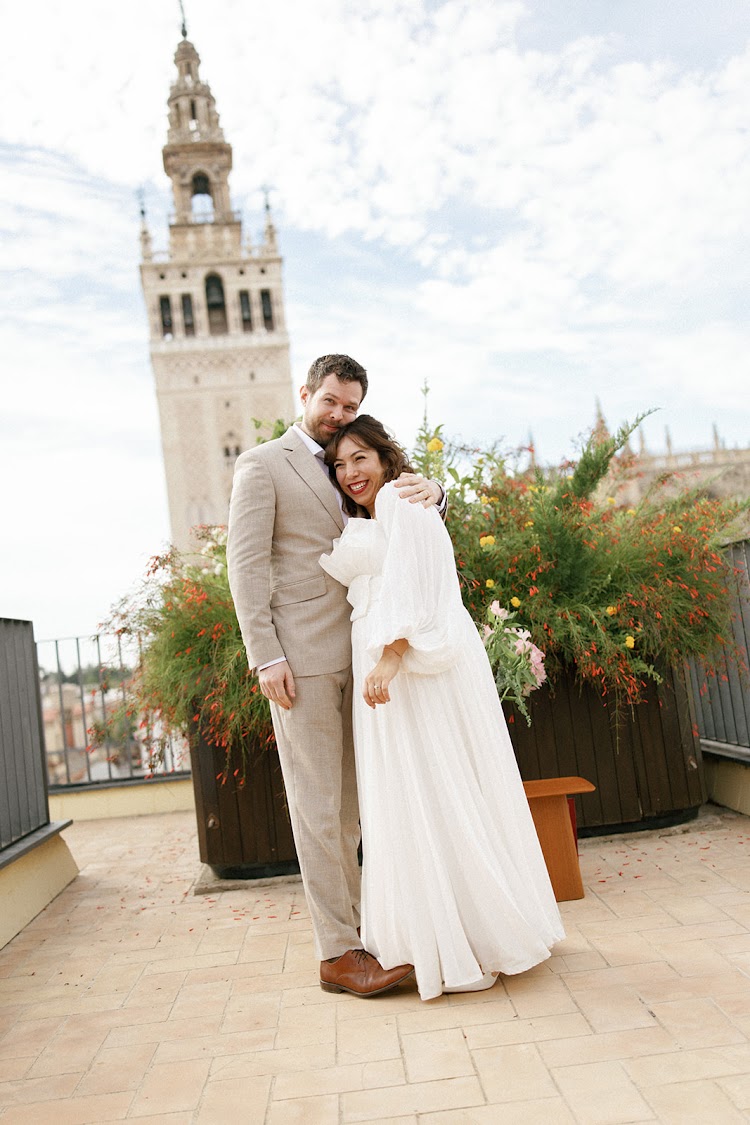 A couple embracing on the terrace of EME Catedral Mercer in Seville with the Giralda tower in the background
