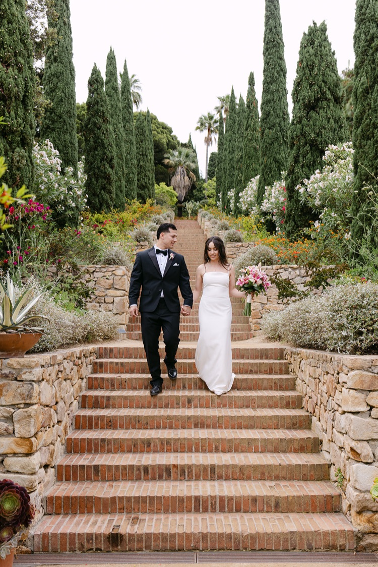A couple walking down a stone stairway between cypress hedges at Marimurtra Botanic Gardens, Costa Brava