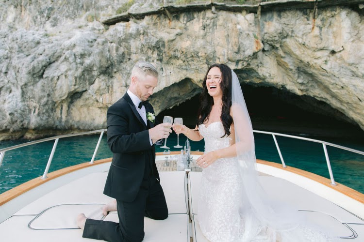 Couple raising a toast on a boat inside a sea grotto on the Amalfi Coast