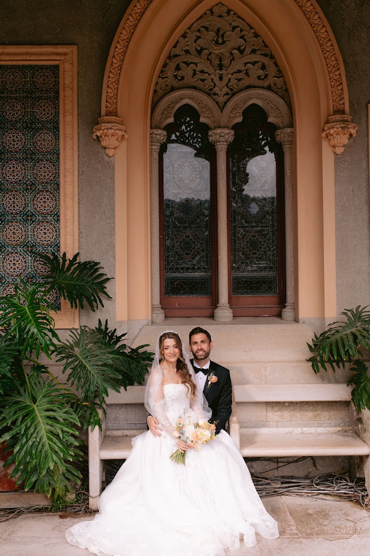 A couple seated before the ornate Moorish windows of Monserrate Palace in Sintra, Portugal