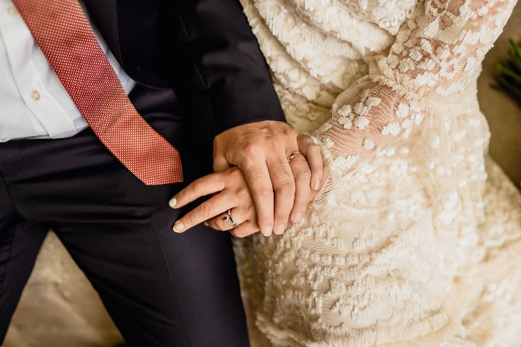 Wedding rings and clasped hands of a couple in the monastery cloister at Poble Espanyol in Barcelona