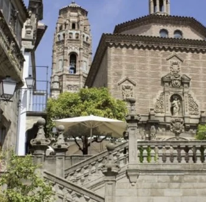 A stone staircase leading up to a church facade and bell tower at Poble Espanyol in Barcelona
