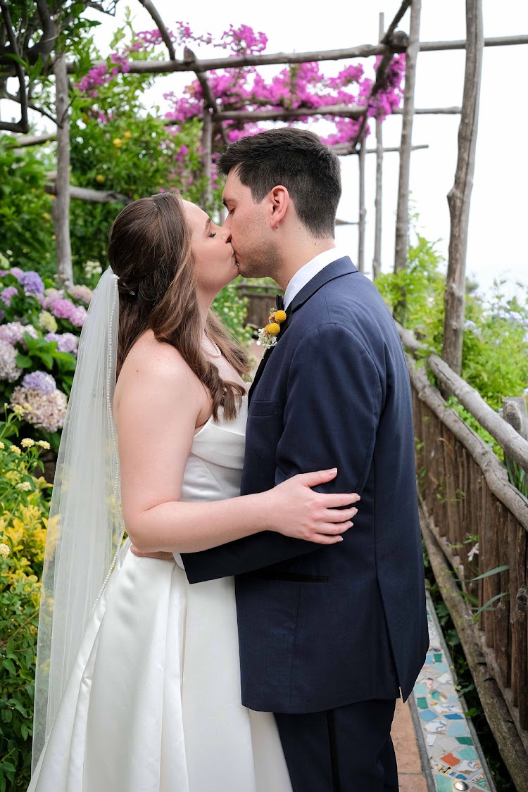 Couple kissing on a bougainvillea-covered garden path at Hotel Santa Caterina on the Amalfi Coast